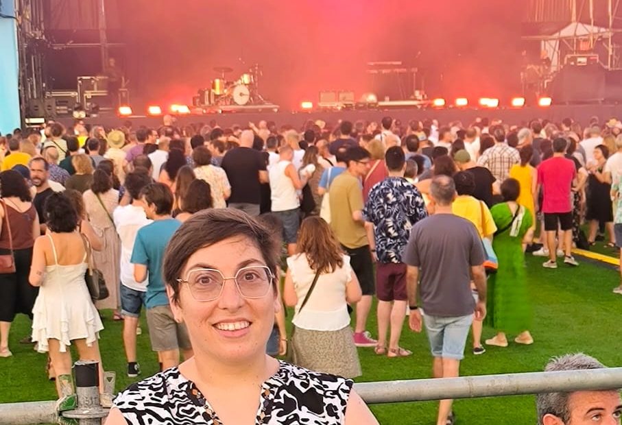 Anna osando en la plataforma reservada para personas con movilidad reducida (PMR) del Festival FAR, con el escenario principal al fondo instantes antes del concierto de Xoel López. La plataforma, situada junto a la torre de control de sonido, ofrece una buena visibilidad del escenario y está rodeada de público sobre una superficie de césped artificial. La imagen ilustra el espacio habilitado para seguir el concierto desde una zona accesible del recinto.